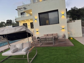 Un edificio moderno con piscina, area salotto all'aperto e zona coperta.