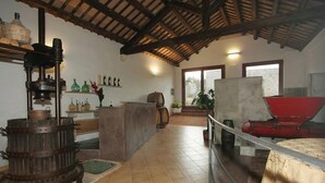 A rustic kitchen with a large wooden beam ceiling, a tiled floor, and various kitchen appliances and utensils. - Agriturismo Tenuta Pizzolungo (Erice)