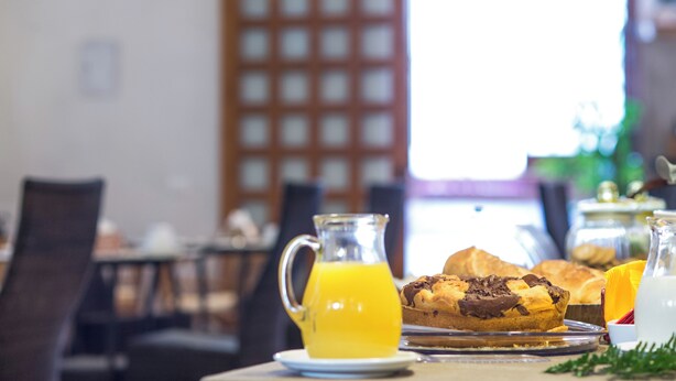 A breakfast setting with a pitcher of orange juice, a muffin, and a glass pitcher on a table. - Agriturismo Tenuta Pizzolungo (Erice)