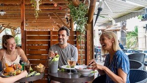 Un espace extérieur aménagé en bois, avec des tables, des chaises et des plantes suspendues.