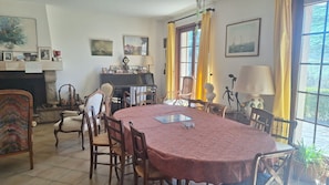 Un espace repas comprenant une table ronde, des chaises, un piano et des œuvres d’art accrochées aux murs.