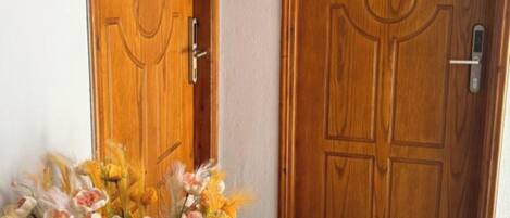 Two wooden doors with numbers 201 and 202, a tiled floor, and a vase with flowers.