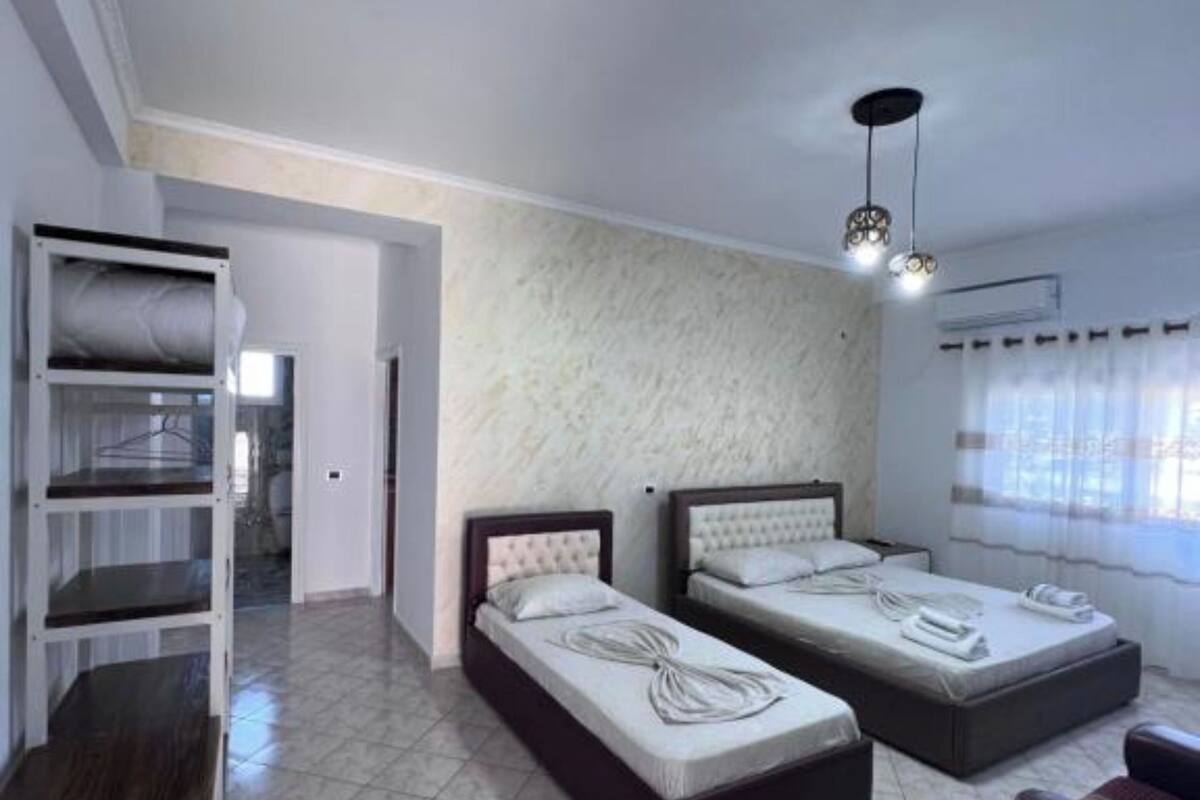 A bedroom with two beds, a wardrobe, and a ceiling light fixture.