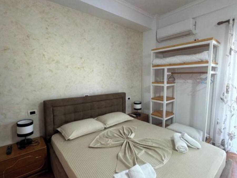 Una cama bien tendida con toallas, una lámpara de noche y una mesita de madera.