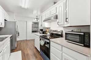 A kitchen with white cabinetry, a stainless steel refrigerator, a microwave, and a stove. - 3BD/2BA w/Gameroom Near FIFA AT&T Stadium-20min to DFW (Grand Prairie)