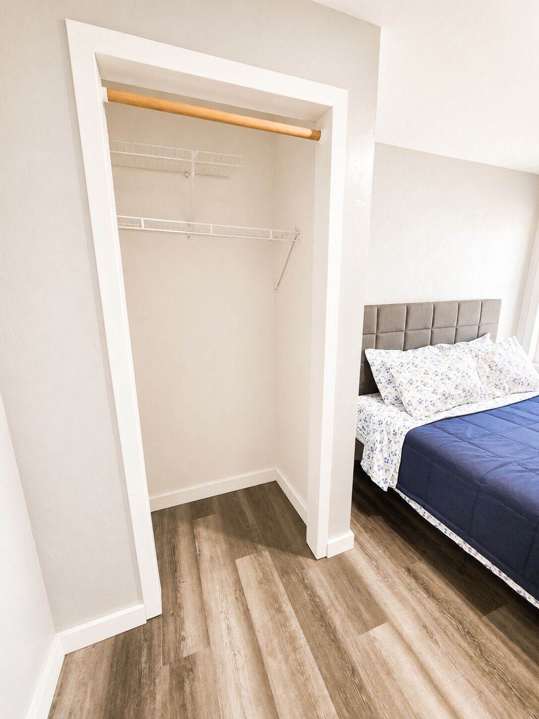 A bedroom with a bed, a wooden closet, and a white headboard.