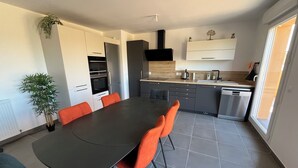 Eine moderne Küche mit Essbereich, ausgestattet mit einem großen Tisch, Stühlen und Einbaugeräten.