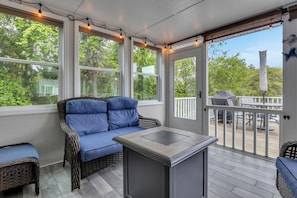 Un patio abrité avec un canapé en osier, une petite table et un espace barbecue.