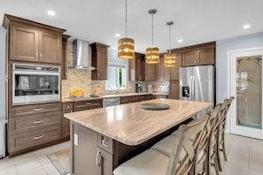 Una cocina moderna con electrodomésticos integrados, armarios de madera e iluminación colgante.
