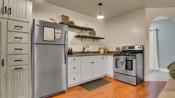 A kitchen with a stainless steel refrigerator, a built-in oven, white cabinets, and a wooden countertop.