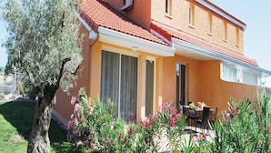 Ein zweistöckiges Gebäude mit rotem Ziegeldach, großen Fenstern und einer überdachten Terrasse.