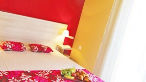 Ein Hotelzimmer mit Bett, Kissen, Nachttisch und Obstteller.