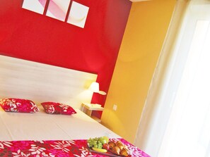 Ein Hotelzimmer mit Bett, Kissen, Nachttisch und Obstteller.