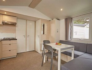 A compact kitchenette with a stove, a dining table with two chairs, and a seating area with a cushioned bench. - Raised Terrace Adriatic Retreat for 4 (Brtonigla)