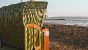 A beachside lounge chair with a number '35' on a post, positioned on a grassy area near the water. - North Sea Dreams Scheper - Dune Oasis (Jever)