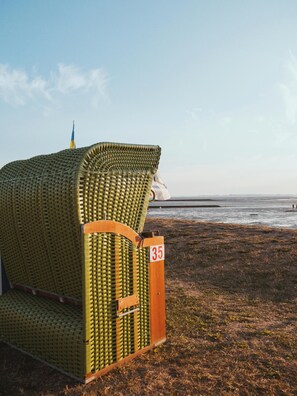 A beachside lounge chair with a woven seat and backrest, marked with the number 35, positioned on a grassy area near the water. - North Sea Dreams Scheper - Dune Oasis (Jever)