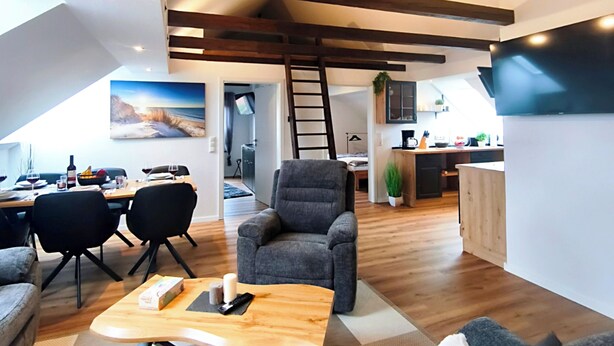 A modern living room with a loft-style ceiling, a dining area, and a kitchen. - North Sea Dreams Scheper - Dune Oasis (Jever)