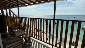 A balcony with a view of the sea, wooden railings, a table, and two wicker chairs. - W cabañas beach, ocean view room 301, two steps from the sea. (Bolívar)