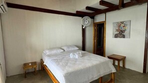 A bedroom with a bed, a small wooden nightstand, a fan, and a door leading to another room. - W cabañas beach, ocean view room 301, two steps from the sea. (Bolívar)
