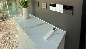 A modern room with a marble countertop, a wall-mounted air conditioner, a power outlet, a control panel, and a vase with flowers. - The Spruce Bliss Pod (Lac du Bonnet)