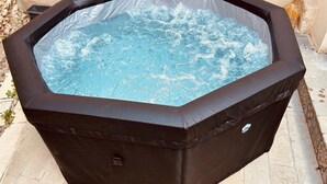 Un bain à remous avec une structure extérieure noire et un panneau de commande visible.