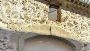 Un bâtiment en pierre doté d’une grande porte en arc de cercle, d’une porte plus petite et d’une fenêtre.