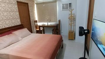 A bedroom with a bed, a desk, a chair, a TV, and a wardrobe.