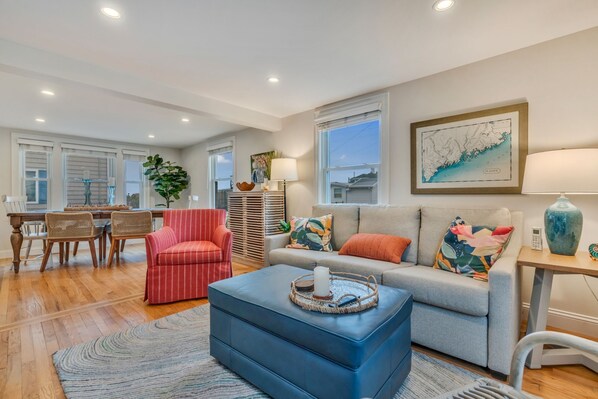 A spacious living room with a sofa, ottoman, and dining area.