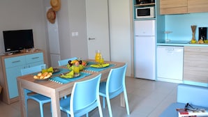 A compact living space with a dining area, kitchenette, and a television. - Marseillan Coastal Duplex for 8 (Marseillan)