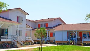 A row of white buildings with red roofs, a grassy area, and a staircase leading to a covered area with bicycles parked underneath. - Marseillan Coastal Duplex for 8 (Marseillan)