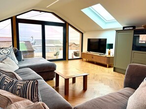 Ein modernes Wohnzimmer mit großem Fenster, Flachbildfernseher und Holzschrank.