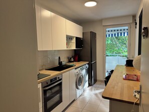Eine kleine Küche mit Waschmaschine, Backofen und Kühlschrank.