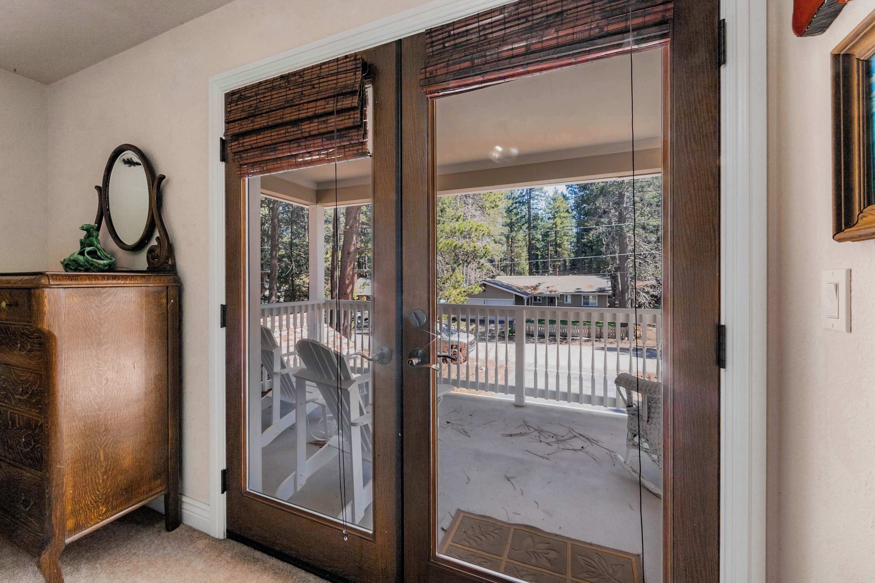 A wooden door with glass panels, a white-framed mirror, and a wooden dresser.