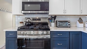 Une cuisine équipée d’une cuisinière en acier inoxydable, d’un four à micro-ondes, d’un grille-pain et de meubles de couleur bleue.