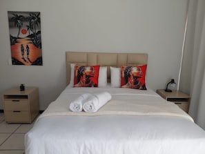 Een hotelkamer met een bed, twee nachtkastjes, een schilderij en een lamp.