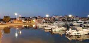 Un port de plaisance avec des bateaux amarrĂ©s, une surface dâeau calme et des bĂątiments en arriĂšre-plan.