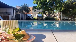 Vista da piscina com uma mesa, cadeiras e uma planta.