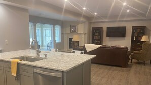 A spacious living area with a large island, a fireplace, and a television mounted on the wall.