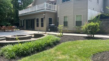 A two-story house with a covered patio and a fire pit.