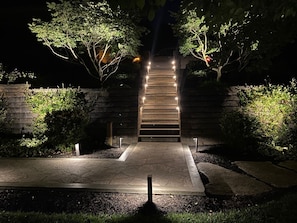 A nighttime outdoor staircase with steps leading up to a building, surrounded by greenery and illuminated by lights. - Conestoga Manor  (Lancaster)