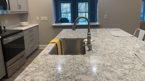 A kitchen with a sink, stove, and cabinets.