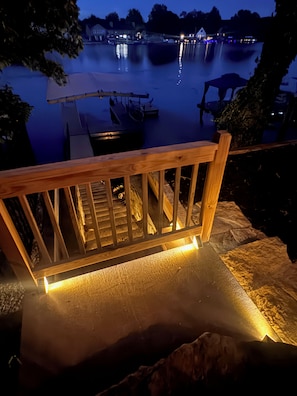 Una terraza de madera con barandilla que da a un cuerpo de agua tranquilo de noche.
