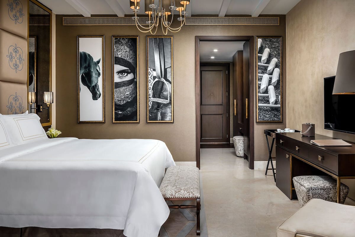 A hotel room with a large bed, a desk, a chair, and a television.