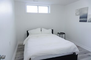 Un dormitorio con cama, una mesita de noche, una ventana y decoración en la pared.