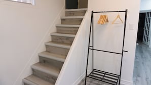 A staircase with wooden steps and a metal rack with hangers. - Modern 3 Bedroom Guest Suite (Toronto)