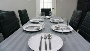 A dining table set for six with plates, cutlery, and wine glasses, surrounded by black chairs. - Modern 3 Bedroom Guest Suite (Toronto)