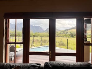 Ein Zimmer mit einer großen Schiebeglastür, die zu einem Außenbereich mit Pool und Bergblick führt.