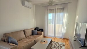 A modern living room with a sofa, coffee table, TV, and a patterned rug. - Urban Comfort Apartments, Podgorica (Podgorica)