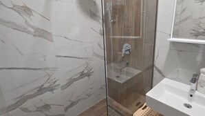 A modern bathroom with a glass-enclosed shower, a sink, and a mirror. - Urban Comfort Apartments, Podgorica (Podgorica)