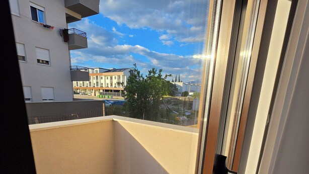 A balcony with a view of buildings and a clear sky. - Urban Comfort Apartments, Podgorica (Podgorica)